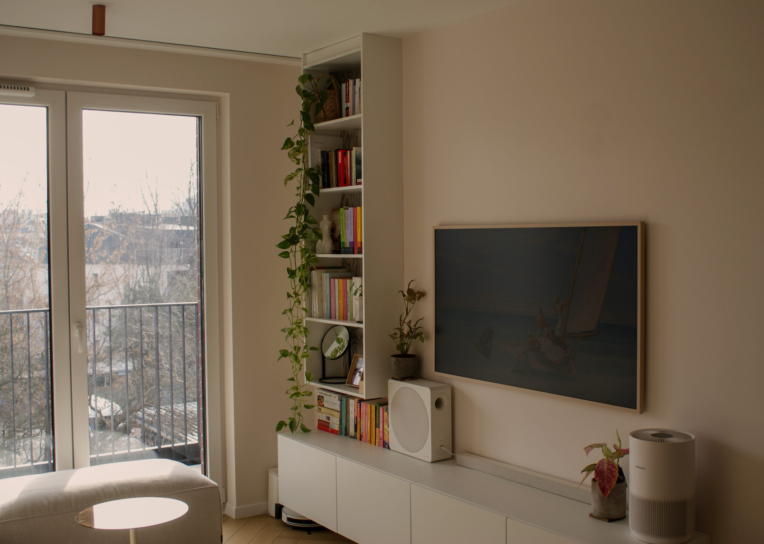 Funkcjonalna zabudowa RTV połączona z regałem na książki w salonie. Wykorzystanie wnęki w małym mieszkaniu w Krakowie.